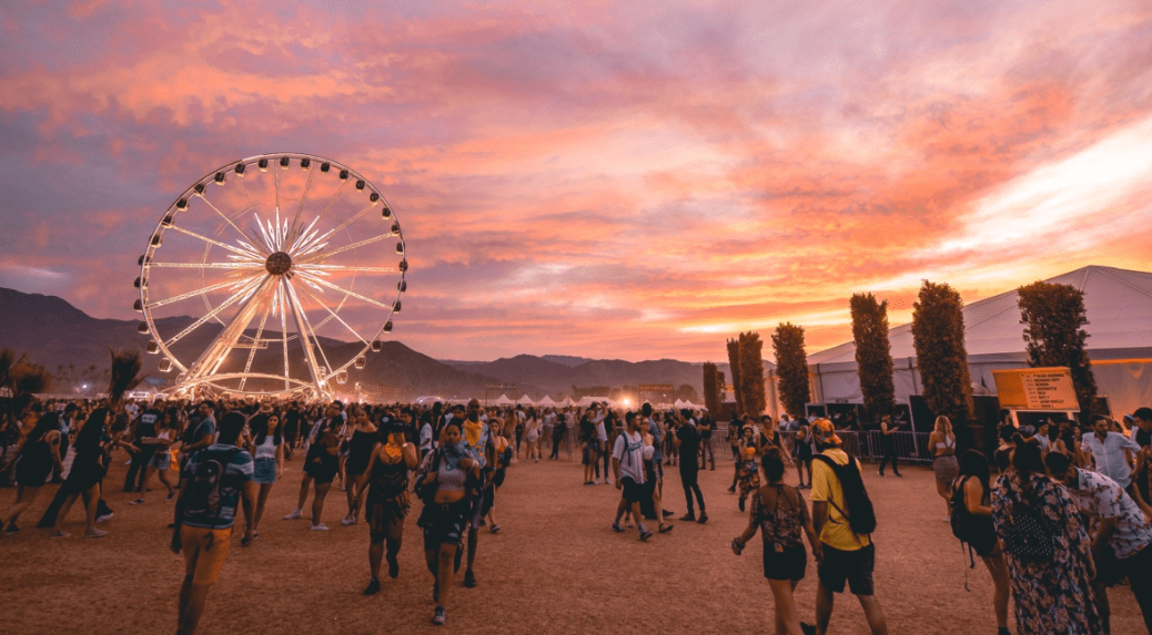 People at a festival during sunset, with a Ferris wheel in the background